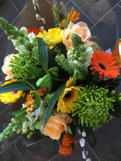 Sunshine Burst - A vibrant and uplifting arrangement inspired by warm, golden days and the rich tones of the changing seasons. Cheerful yellows and bold oranges are beautifully complemented by fresh greenery and soft, neutral accents, creating a lively and energetic display. The mix of textures and natural movement gives this piece a dynamic, just-gathered feel, while still maintaining a polished finish. Perfect for brightening any space or celebrating joyful moments, it radiates warmth, positivity, and seasonal charm.